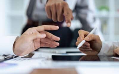 Des mains autour d’une tablette montrent la validation d’un document, avec un stylet et un geste de coordination lors d’une signature électronique.
