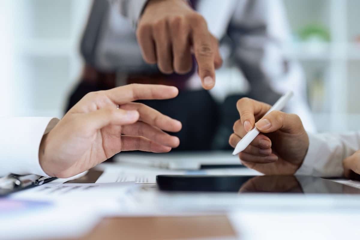 Des mains autour d’une tablette montrent la validation d’un document, avec un stylet et un geste de coordination lors d’une signature électronique.