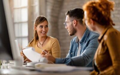 Autour d’une table de travail, une équipe de jeunes entrepreneurs échange sur un contrat dans une ambiance de collaboration et de développement des PME.