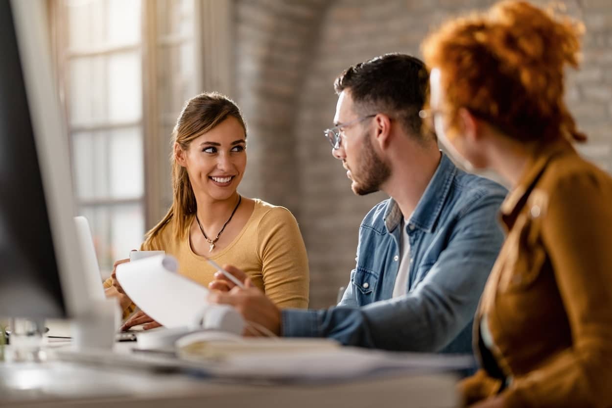 Autour d’une table de travail, une équipe de jeunes entrepreneurs échange sur un contrat dans une ambiance de collaboration et de développement des PME.
